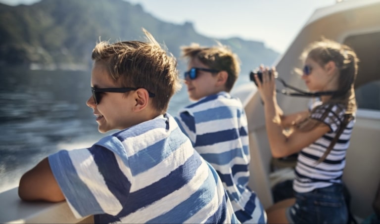 Kinder genießen die Aussicht auf dem Sonnendeck der MS Mondseeland bei einer Schifffahrt.
