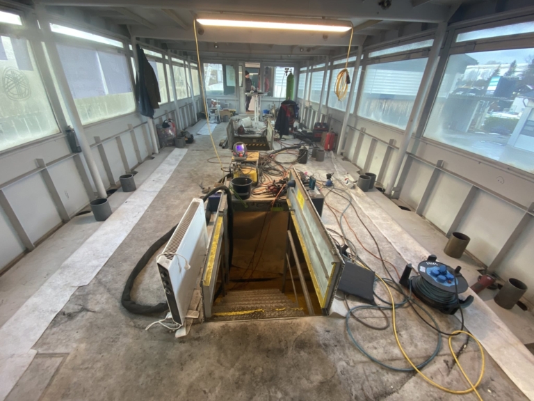Totalerneuerung der Kabine des Passagierschiff MS Mondseeland im Winter 2021. Die Kabine ist völlig leer. Es liegen viele Kabel und Geräte herum. Die Fenster sind beschlagen. Eine offene Luke führt in den Maschinenraum.